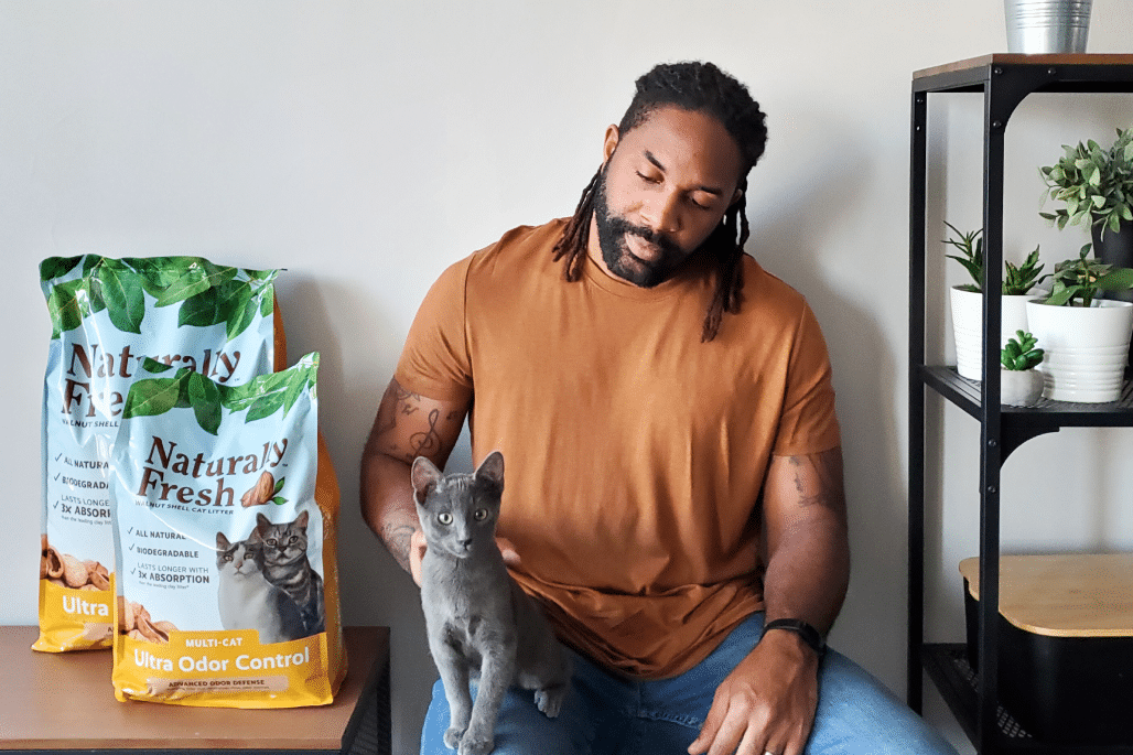 Instagram influencer Abdul from Abdul's Cats posing with a cat, next to a bag of Naturally Fresh cat litter